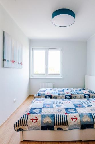two beds in a bedroom with white walls at Yacht Apartments Kapitański in Wilkasy