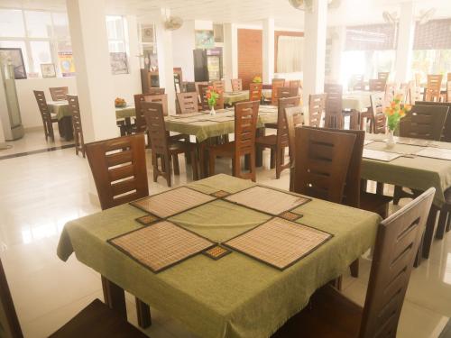 a restaurant with tables and chairs with green table cloth at Visaka Hotel - Kataragama in Kataragama