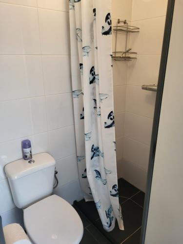 a bathroom with a toilet and a shower curtain at Beach-house27 in Egmond aan Zee