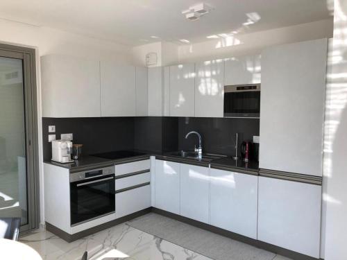 a kitchen with white cabinets and a sink at Saint Jhon in Menton