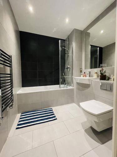 a bathroom with a toilet and a shower and a sink at Private room in modern flat in great location in London