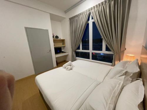 Cama blanca en habitación con ventana grande en Husfa Mahkota Valley Studio Suite, en Kuantan