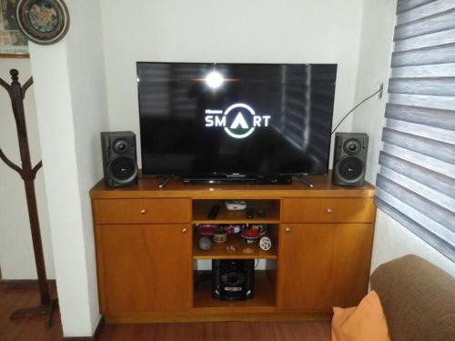 a flat screen tv on a wooden entertainment center with speakers at Finca Mc'Clau Teotihuacan, Casa residencial entera in San Martín de las Pirámides