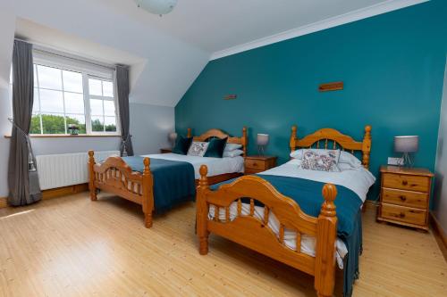 1 dormitorio con 2 camas y pared azul en Michaeleen's Manor B&B, en Cong