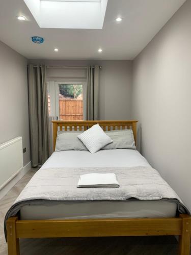 - une chambre avec un lit avec un cadre en bois et une fenêtre dans l'établissement Stunning semi detached bungalow in West Wimbledon, à Londres