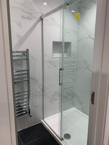 La salle de bains est pourvue d'une douche avec une porte en verre. dans l'établissement Stunning semi detached bungalow in West Wimbledon, à Londres