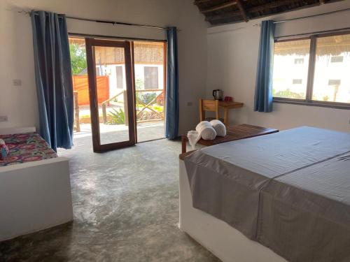 a bedroom with a bed and a large window at Kokopelli Bungalows in Nungwi