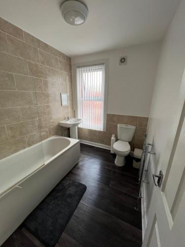 La salle de bains est pourvue d'une baignoire, de toilettes et d'un lavabo. dans l'établissement Leeds Serviced Accommodation, à Killingbeck