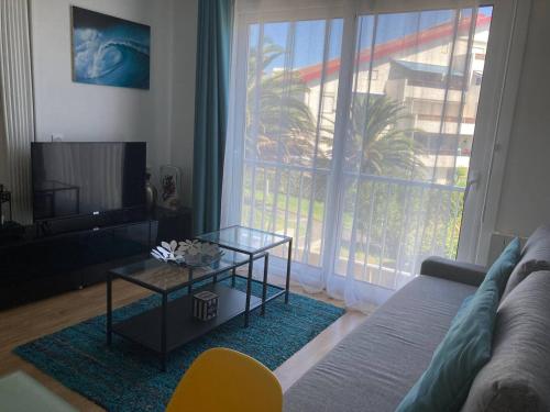 sala de estar con sofá, mesa y ventana grande en Ocean Marbella Beach, en Biarritz