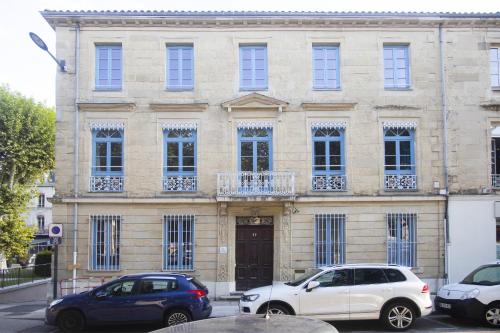 a building with two cars parked in front of it at Le Jules Appart'Hotel in Romans-sur-Isère