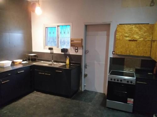 a kitchen with black cabinets and a sink and a stove at Villa Bonapriso avec piscine in Douala