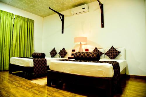 1 dormitorio con 2 camas y cortina verde en The Grand Leisure, en Iluppankadawala
