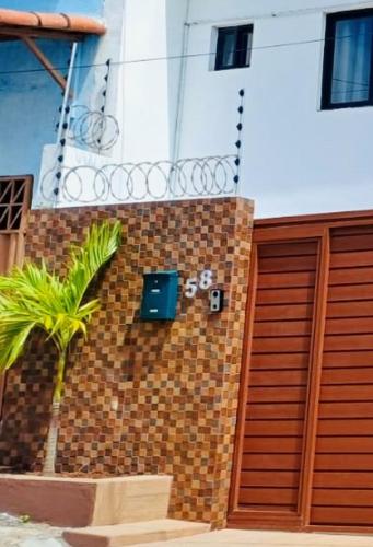 a brick building with a gate and a palm tree at Residence Pipa Beach in Pipa