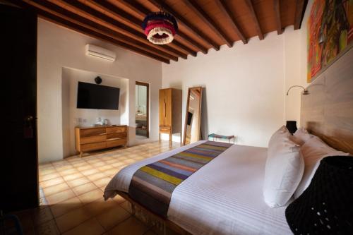 a bedroom with a large bed and a television at NaNa Vida Hotel Oaxaca in Oaxaca City