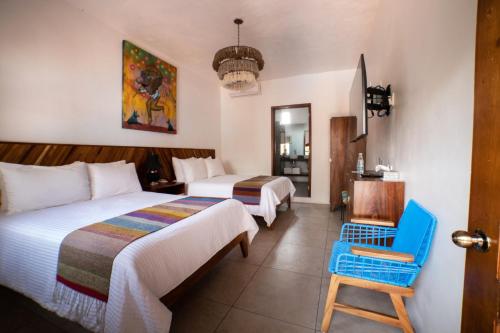 a hotel room with two beds and a blue chair at NaNa Vida Hotel Oaxaca in Oaxaca City