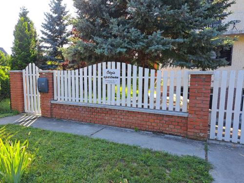 a white picket fence with a brick wall and a gate at Apartment Oase in Balatonszemes