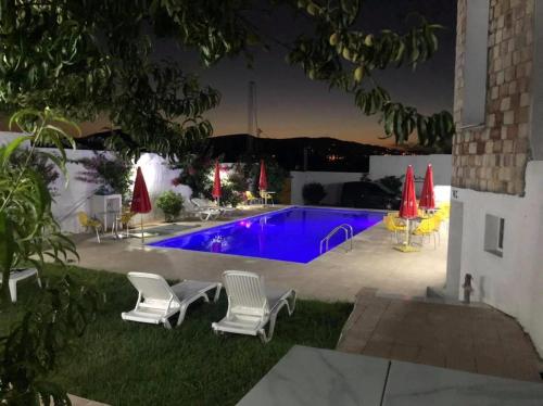 a swimming pool at night with chairs and umbrellas at NN Residence Tabarka in Tabarka