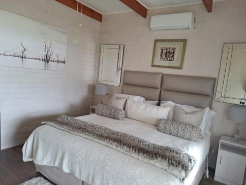 a bedroom with a large white bed with pillows at Milky Way Executive Suite in Sandbaai