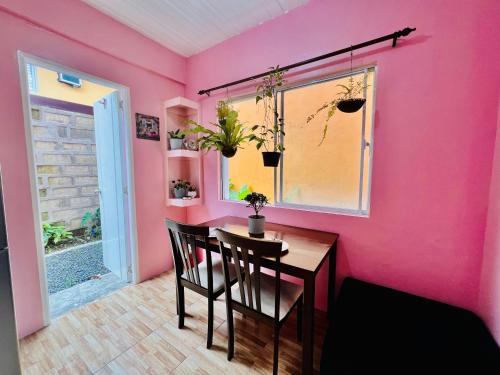 a dining room with pink walls and a table and chairs at Cara Transient house in San Pablo