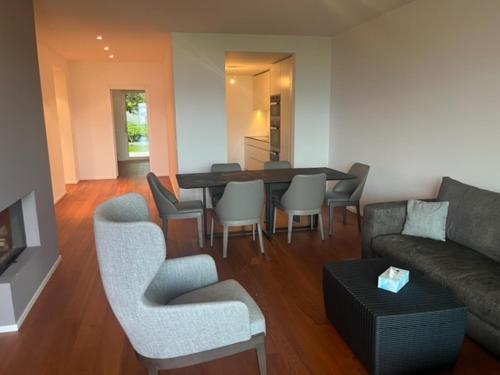 ein Wohnzimmer mit einem Sofa, einem Tisch und Stühlen in der Unterkunft Luxusapartment an Traumlage in Lugano in Paradiso