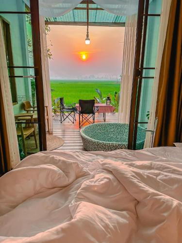 a bed in a room with a view of a patio at Nana Field cabin 1 in Ban Phra Fang