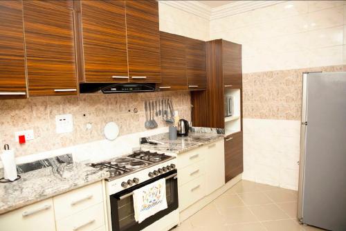 a kitchen with wooden cabinets and a stove top oven at Duke Diamonds Apartments in Abuja