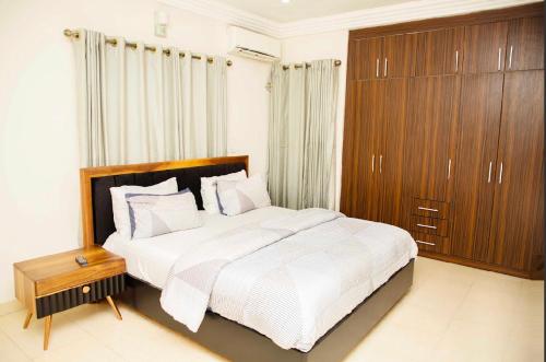 a bedroom with a large bed and a wooden cabinet at Duke Diamonds Apartments in Abuja