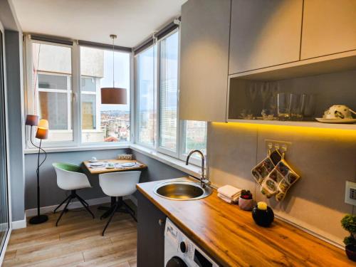 cocina con fregadero, escritorio y ventanas en CharmAntique Apartments, en Tirana