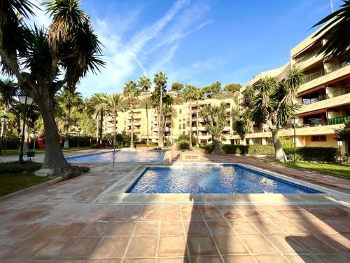 a swimming pool with palm trees in front of a building at Rosa Nautica 106 in La Herradura