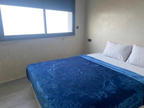 een slaapkamer met een bed met een blauwe deken erop bij Amouage résidence in Sidi Ifni