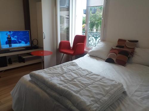 een slaapkamer met een bed, een televisie en een stoel bij A.B.C ROOM SERVICES in Garges-lès-Gonesse