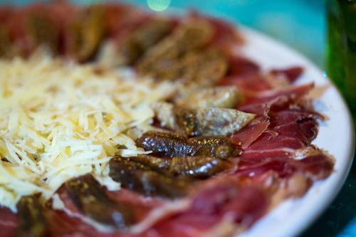 a plate of food with meat and cheese on a table at Abayomi Hotel in Ilhabela