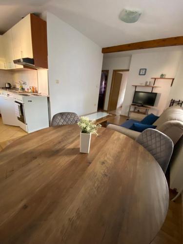 a living room with a large wooden table and a kitchen at Apartman Željo in Livno