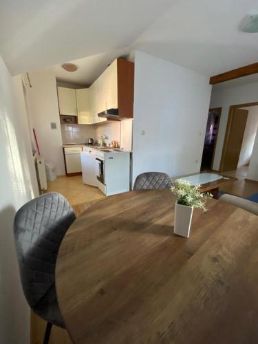 a dining room table with chairs and a kitchen at Apartman Željo in Livno