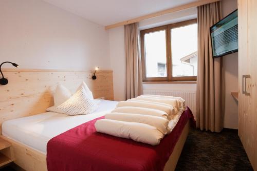 a bedroom with a bed with white sheets and a window at Falkner Appartement Resort in Längenfeld