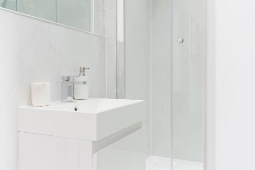 a white bathroom with a sink and a mirror at Welcome London Carnaby Street in London