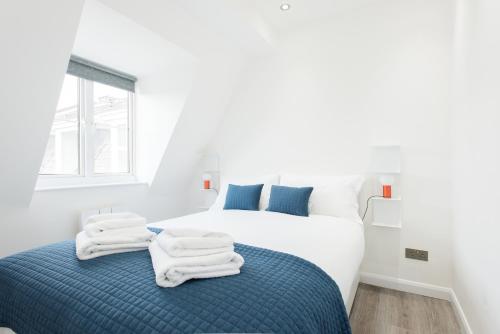 a white bedroom with two beds with towels on the bed at Welcome London Carnaby Street in London