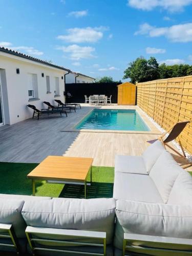 a patio with a couch and a table and a pool at Maison Piscine Spa près bordeaux in Ambarès-et-Lagrave