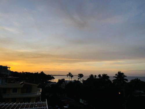 a view of the ocean at sunset with palm trees at Hotel Neptuno Refugio in Boca Chica