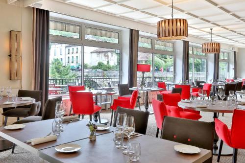 un restaurant avec des tables et des chaises rouges et des fenêtres dans l'établissement Hotel Restaurant Charbonnel, à Brantôme