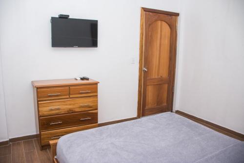 a bedroom with a bed and a dresser and a tv at Chango's Apartments in Bocas del Toro