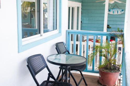 a glass table and two chairs on a porch at Chango's Apartments in Bocas del Toro