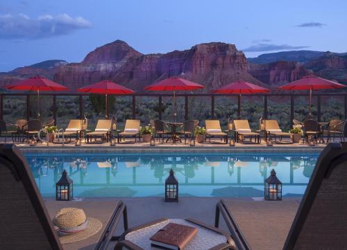 a beach with a pool, chairs, and tables with umbrellas at Capitol Reef Resort in Torrey