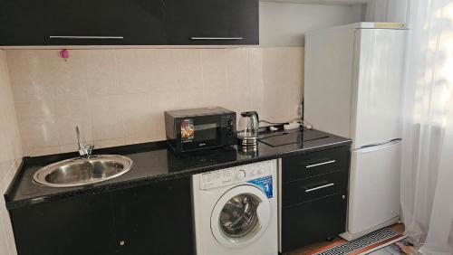 eine Küche mit einer Waschmaschine und einem Waschbecken in der Unterkunft 1 комн. квартира центр in Semei
