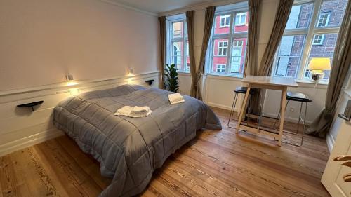 a bedroom with a bed and two windows and a desk at Boutique Apartments 1 - 8 in Copenhagen