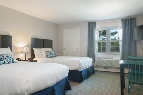 Kittery Inn & Suites في كيتري: غرفة فندقية بسريرين ونافذة