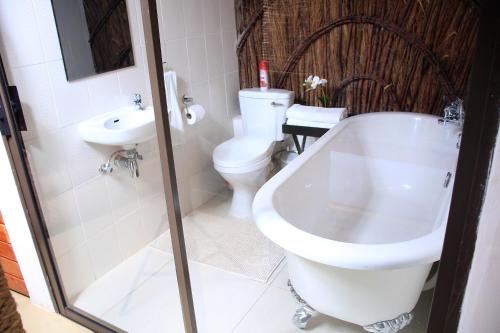 y baño con aseo, bañera y lavamanos. en Olive Country Lodge - Eswatini, en Ngwempisi
