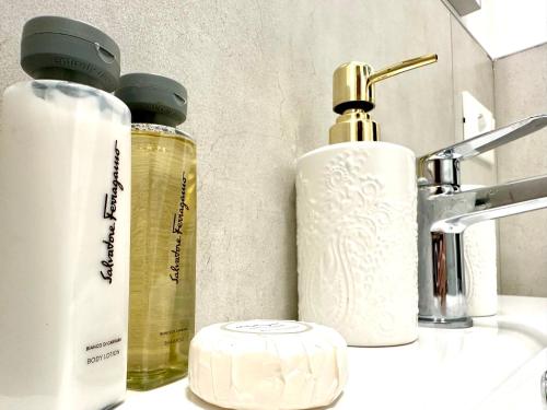 een badkamer met 2 flessen zeep en een wastafel bij Beach Front Apartment Sabbiadoro in Lignano Sabbiadoro