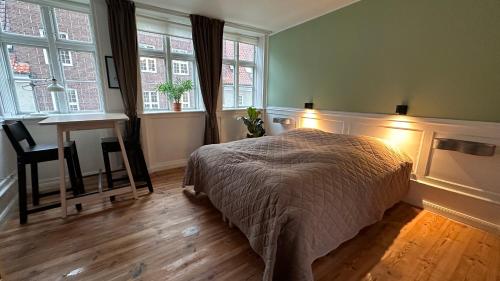 a bedroom with a bed and a desk and windows at Fantastiske Christianshavn in Copenhagen
