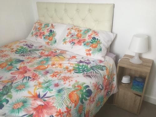 una cama con un edredón colorido con un patrón de pájaro en Tamaras Place en Leysdown-on-Sea